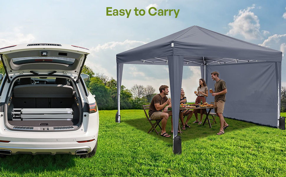 Grey pop-up canopy tent with side panel set up on grass, shown next to an SUV with open trunk, demonstrating portability and outdoor use. People gathered under tent at folding table.