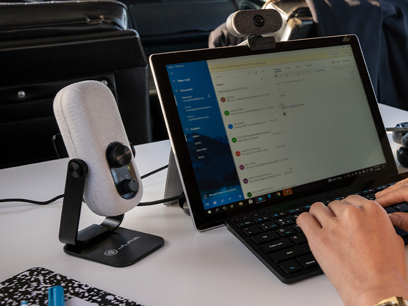 Go talk mic on a white table next to a tablet and person typing on a keyboard