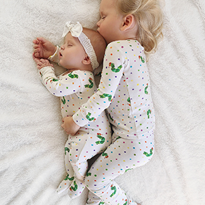 image of 2 siblings sleeping on bed, both wearing caterpillar print from collection