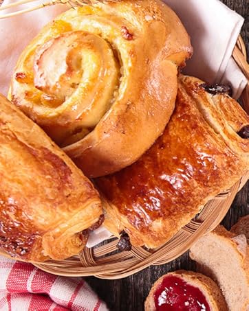 una mesa con croissants, mermelada y pan