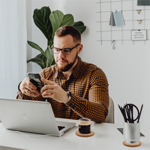 A man sits at a desk with coasters and coffee.