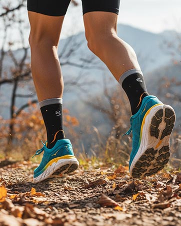 SPIRESNUG runner's legs in black orange socks on trail. Close-up detail.