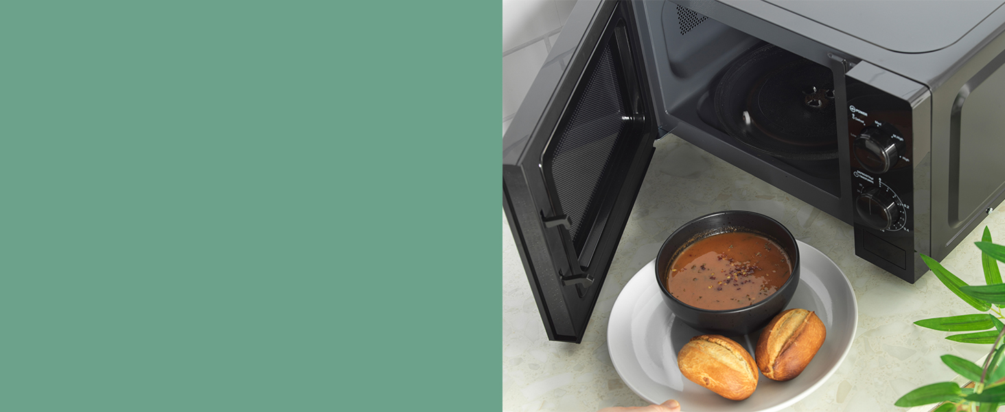 image of the bowl of of soup infront of the open progress black microwave showing the inside 