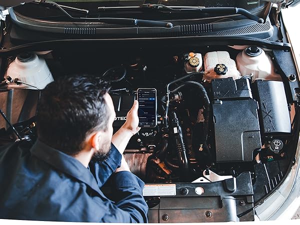 Mechanic using BLuedriver's iphone app to diagnose check engine light while looking at engine