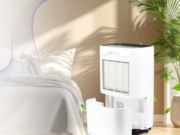 White portable air purifier or humidifier unit positioned near a bed, with sunlight casting shadows on the wall.