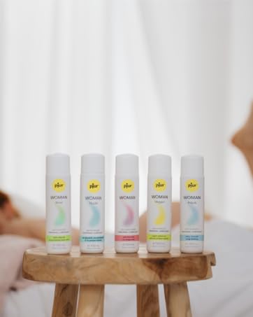 Five identical cylindrical bottles with yellow caps arranged in a row on wooden stool, each containing different colored liquids.