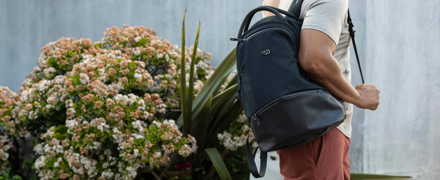 Guy wearing backpack by a flower bush