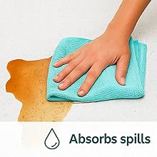 Microfiber cloth absorbing a large liquid spill on a wooden surface.