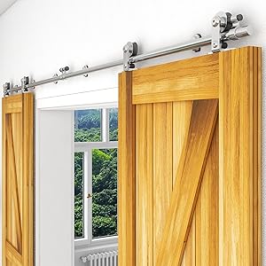 Wooden barn door with metal sliding hardware. Door features a Z-brace design, mounted on a white wall next to a window overlooking green foliage.