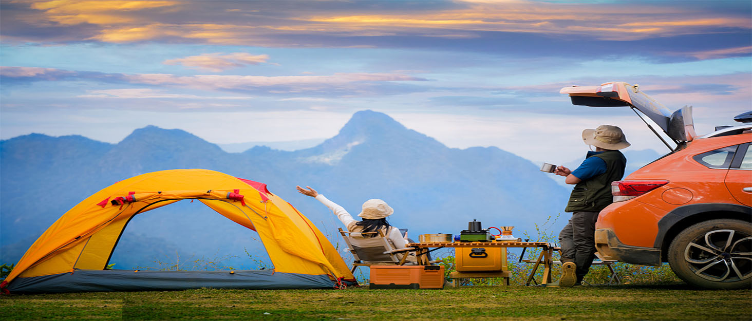Scène de camping avec tente orange et SUV orange sur fond de paysage de montagne au coucher du soleil, équipement de camping visible au premier plan