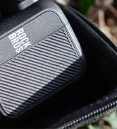 Multiple views of a black striped gaming console or device with sleek, modern design shown from different angles against dark backgrounds.