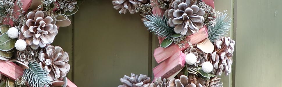 a wreath with pine cones and pinecones on a green door