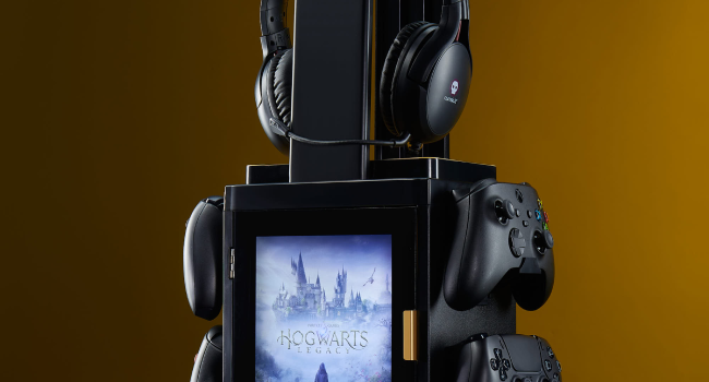 Gaming setup with headphones, controller, and smartphone mounted on a stand. Screen displays a winter cityscape scene.
