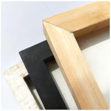 Three wooden frames in natural, black, and white, stacked at an angle.