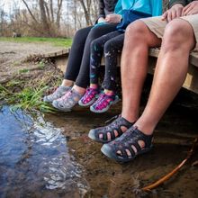 people wearing sandals on a dock near water.