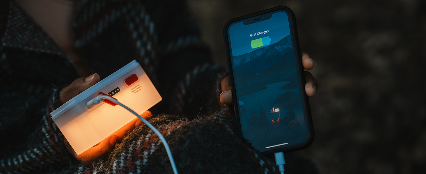 Person holding an LED light that is charging a smartphone
