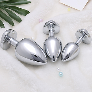 Drei silberne Analplugs in verschiedenen Größen, die auf einer weißen Oberfläche angeordnet sind. Die Stecker haben eine Tropfenform mit ausgestellter Unterseite aus Sicherheitsgründen