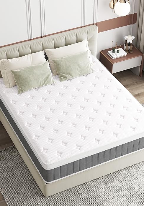 Queensize-Matratze mit weißer Steppdecke auf einem beigen gepolsterten Bettgestell. Das Schlafzimmer ist mit hellgrünen Kissen