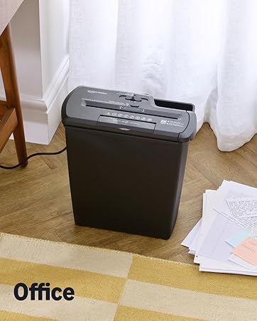 Der Text lautet „Büro“. Mehrere Ansichten eines Aktenvernichters in einer Büroumgebung mit hellem Holzboden und weißen Wänden.