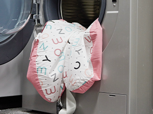 Weißes mechanisches Gerät mit rosafarbenen Akzenten an einer grauen Wand.