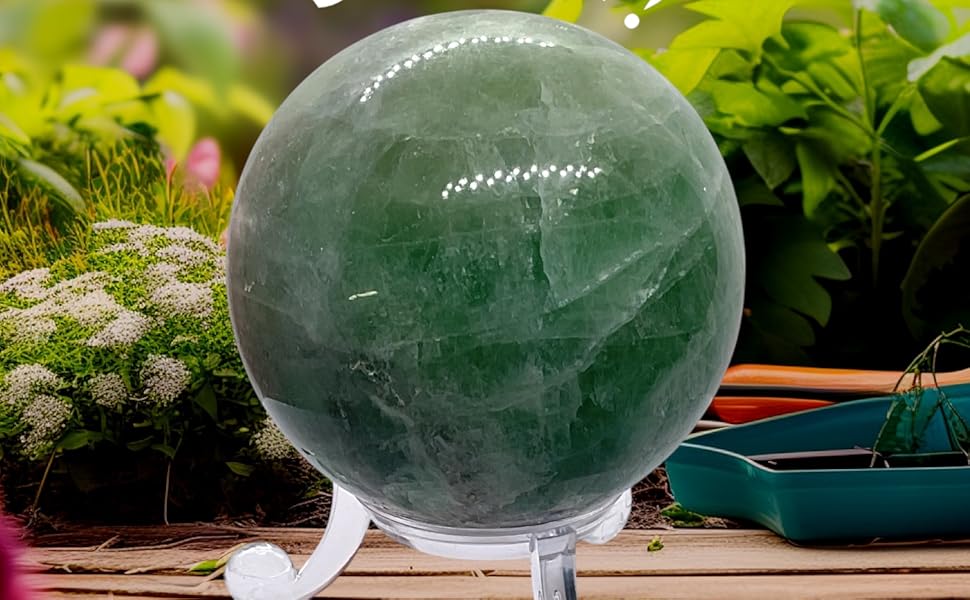 Der Text lautet „STREET“. Objekt in Form eines Fußballs aus grünem Glas oder Kristall, fotografiert auf einer Holzoberfläche im Freien mit natürlichem Licht.