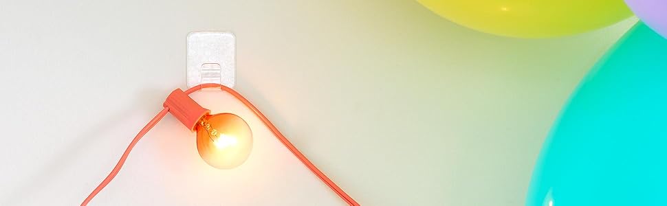 Command Adjustables holding a string of lights on the wall next to balloons.