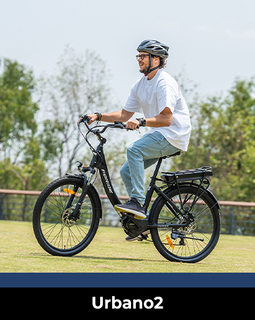 Person, die ein schwarzes Elektrofahrrad auf einem Grasweg fährt und ein weißes Poloshirt, eine Jeans und einen Helm trägt.