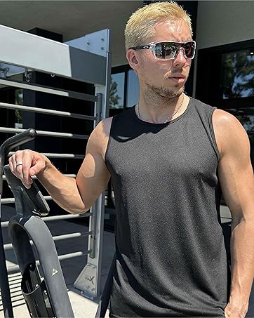 Person wearing sunglasses and a gray sleeveless shirt standing next to exercise equipment outdoors.