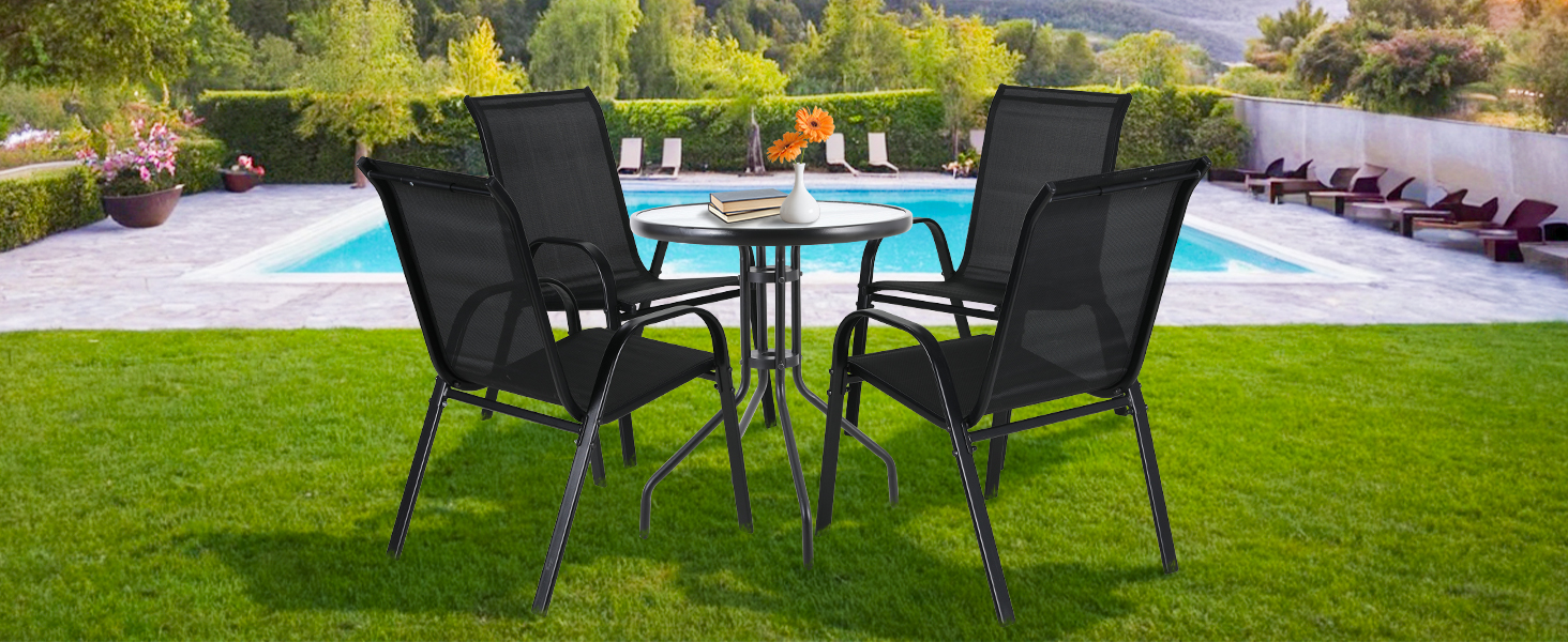 avec table ronde en verre et quatre chaises en maille noire. Situé près de la piscine dans un jardin paysager.