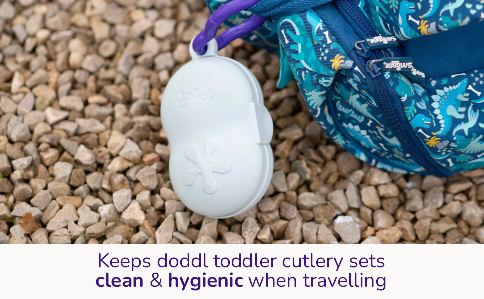Image of the doddl toddler cutlery travel case clipped to a bag on a pile of pebbles.