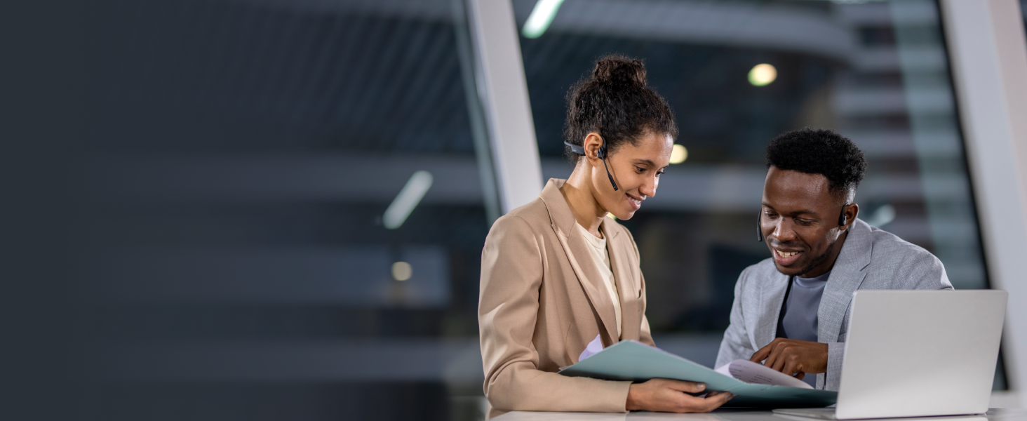 eine Frau, die ein Headset trägt und auf einen Laptop schaut