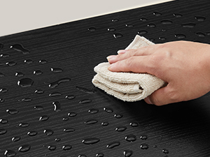 Tmavý povrch utrite ručne svetlou handričkou. Na povrchu budú viditeľné kvapky vody, čo naznačuje vodoodpudivé alebo ľahko čistiteľné vlastnosti.