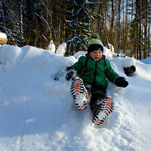 In winter snow, a boy in black knit gloves skis happily, playing comfortably.