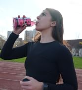 athlete drinking protein sports drink on an outdoor track