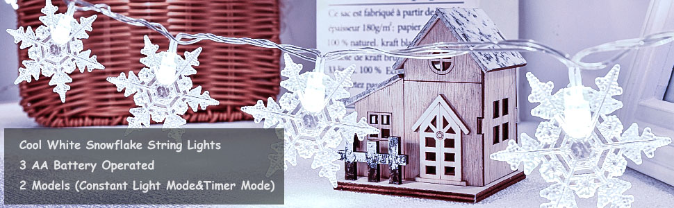 White wooden house-shaped Christmas decoration with LED lights, alongside packaging mentioning 'Cool White Snowflake' and battery operation.