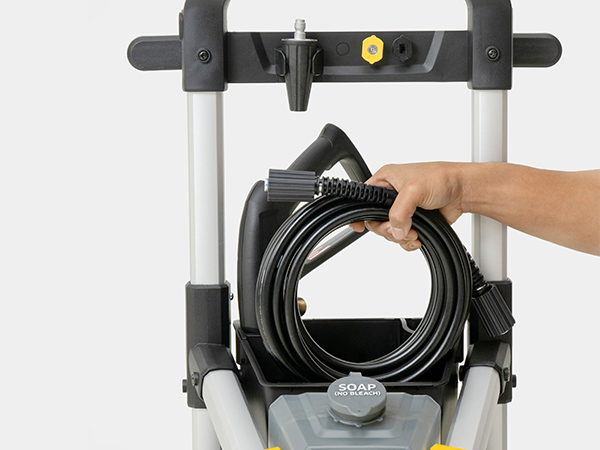 A person placing the pressure washer hose in the onboard storage bin