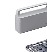 Dispositivo rectangular gris portátil con asa, probablemente un aparato electrónico o un altavoz. La segunda imagen muestra un primer plano del borde inferior del dispositivo