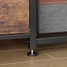 Close-up view of a black metal furniture leg or support against wooden flooring and tile, showing structural detail.
