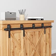 Schiebesystem für Scheunentore aus Holz, am Schrank montiert. Schwarze Metallschiene mit Rollen auf hellen Holztüren mit X-Muster