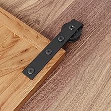 Beschläge für Scheunentore aus schwarzem Metall, montiert auf Holzböden. Verfügt über eine flache Schiene mit Rad für den Schiebetürmechanismus.