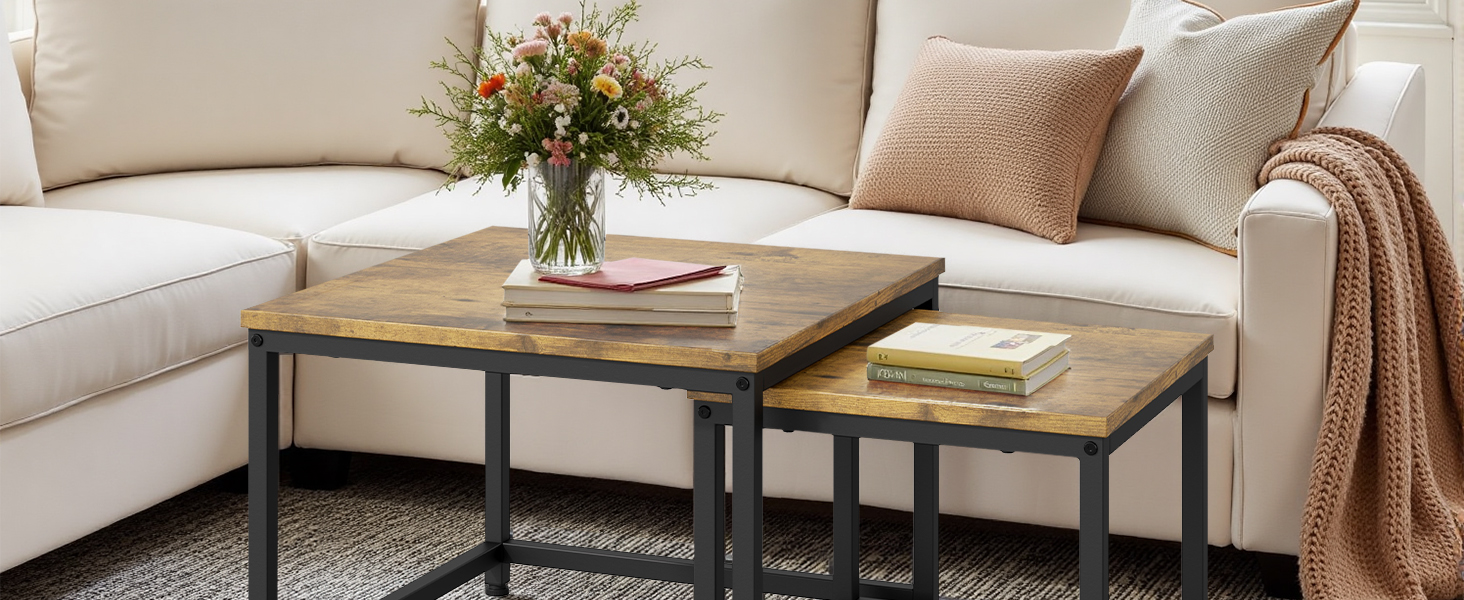 Living room scene with neutral L-shaped sectional sofa, beige throw pillows, and industrial-style nesting coffee tables with wood tops. Fresh flower arrangement adds natural accent.