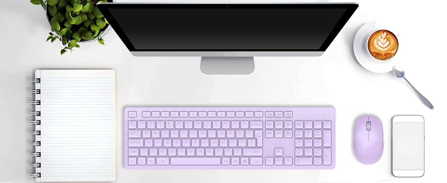 Desktop workspace with black monitor, lavender keyboard and mouse, notepad, smartphone, coffee cup, and plant. Clean, organized setup on white surface.