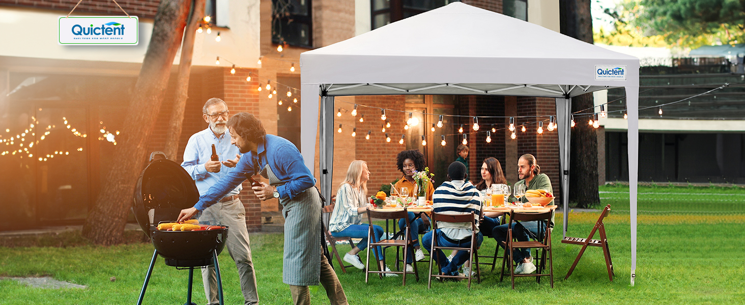 White pop-up canopy tent set up outdoors with string lights, providing shelter for outdoor dining on grass with tables and chairs.