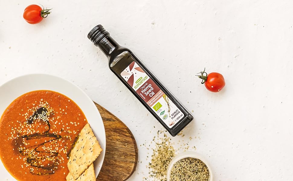 Boal of tomato soup on the wooden board on the table with garlic oil and shelled hemp seeds