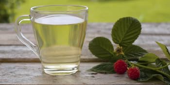 un vaso de agua junto a una fresa.
