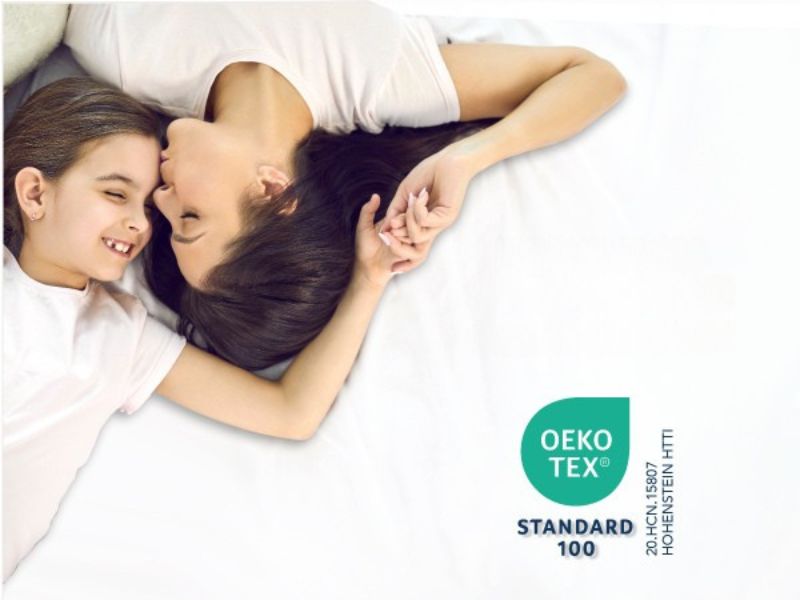 Auf dem Text steht das Logo „OEKO STANDARD 100“, das in der unteren Ecke sichtbar ist. Innenausstattung des Schlafzimmers mit sanfter Beleuchtung.