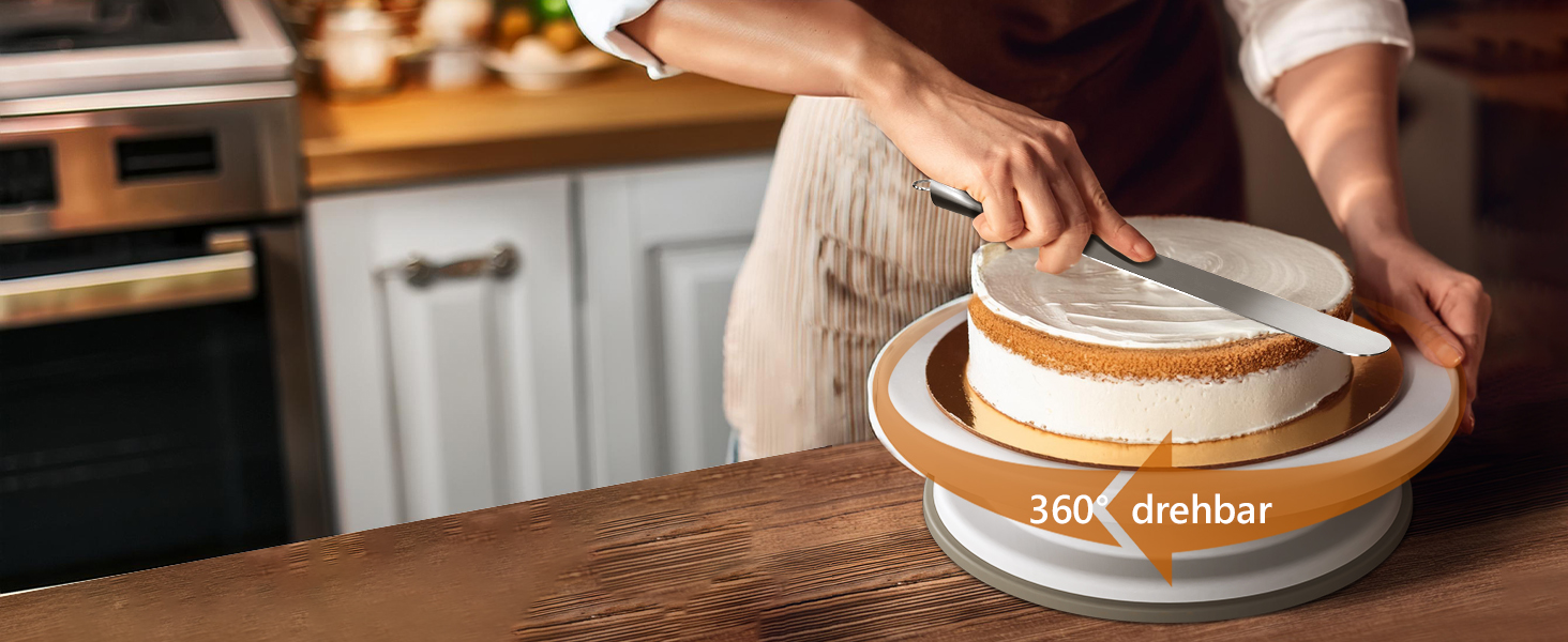 Hände legen einen runden weißen Kuchen auf eine orangefarbene Kuchendrehteller-Plattform im Küchenbereich.