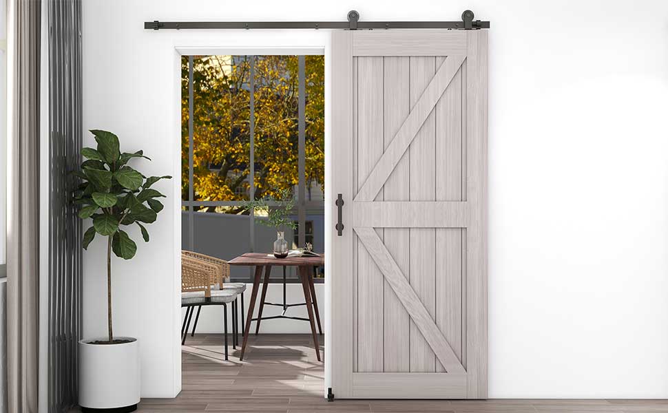 White barn-style sliding door with X-pattern design. Black hardware mounted on top. Opens to reveal dining area with autumn view through window.