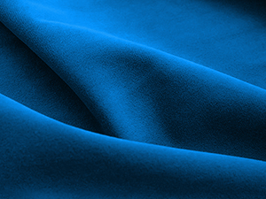 Close-up of a bright blue fabric with soft, wavy folds creating a rippled texture pattern on a dark background