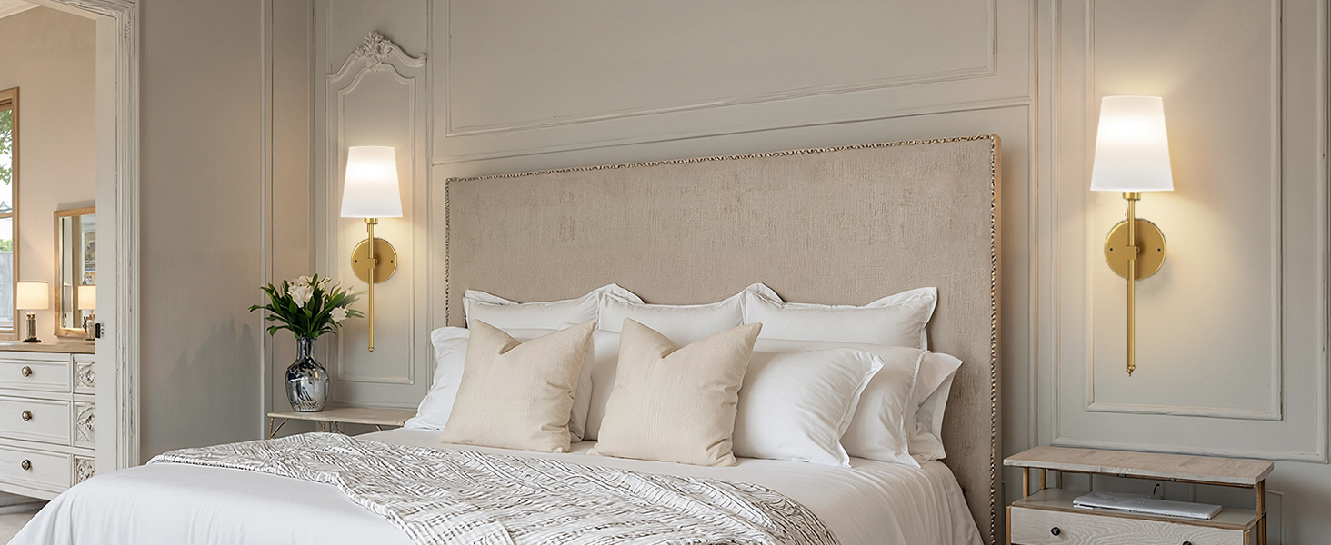 Luxurious hotel-style bedroom interior with white bedding, cream walls, gold sconce lighting fixtures, and elegant furnishings creating symmetrical design.